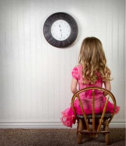 A young child in time out or in trouble, with clock on wall