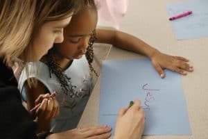 Young girl writing Jesus on a piece of paper. She is in baptism class, but is she ready to be baptized.